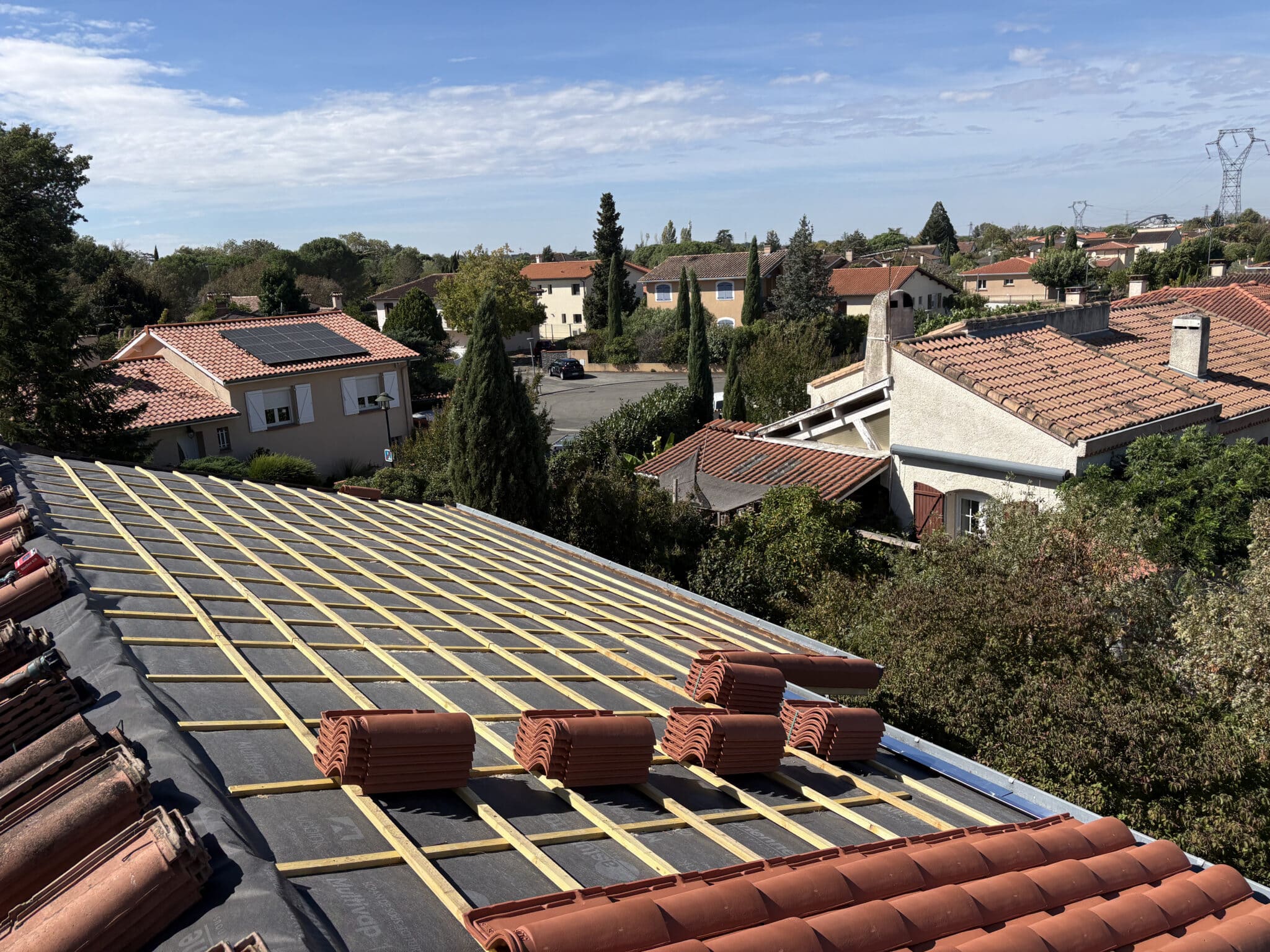 Pose des tuiles en terre cuite sur une toiture en rénovation à Portet-sur-Garonne (31).